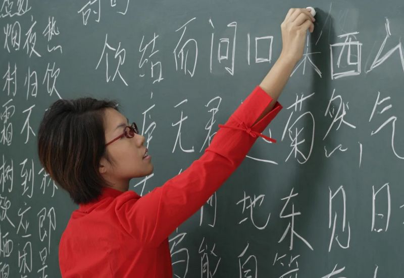 Девушка азиатка пишет не доске иероглифы